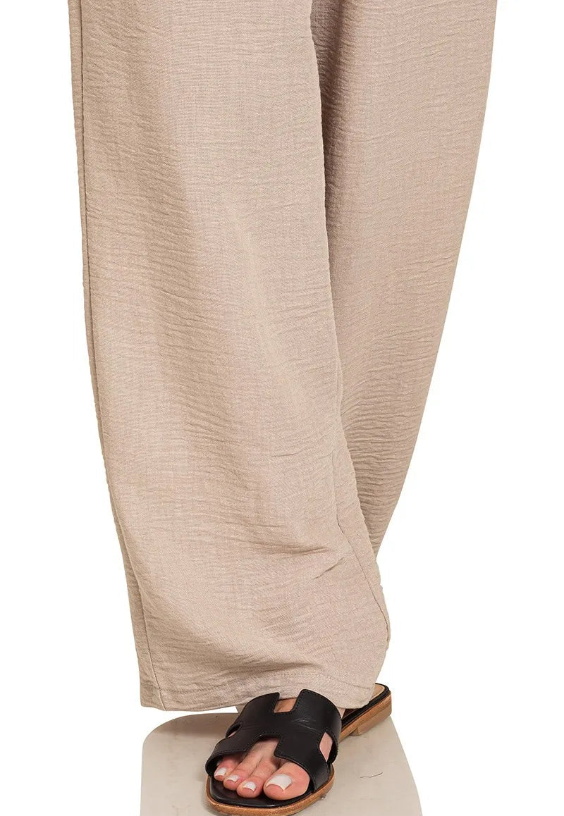 Beige pants worn with a black sandal on a white background