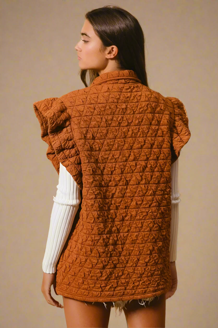 Woman wearing a brown quilted vest against a beige background
