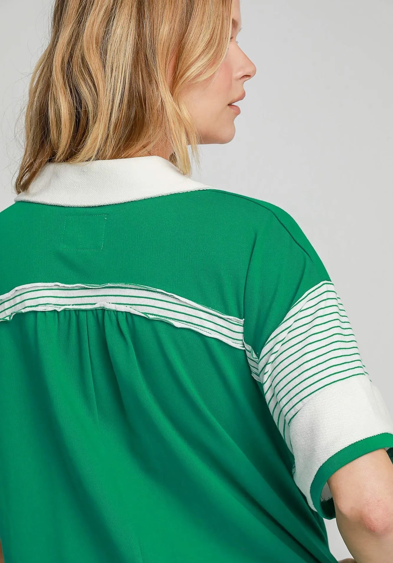 Green and white polo shirt worn by a person on a light gray background