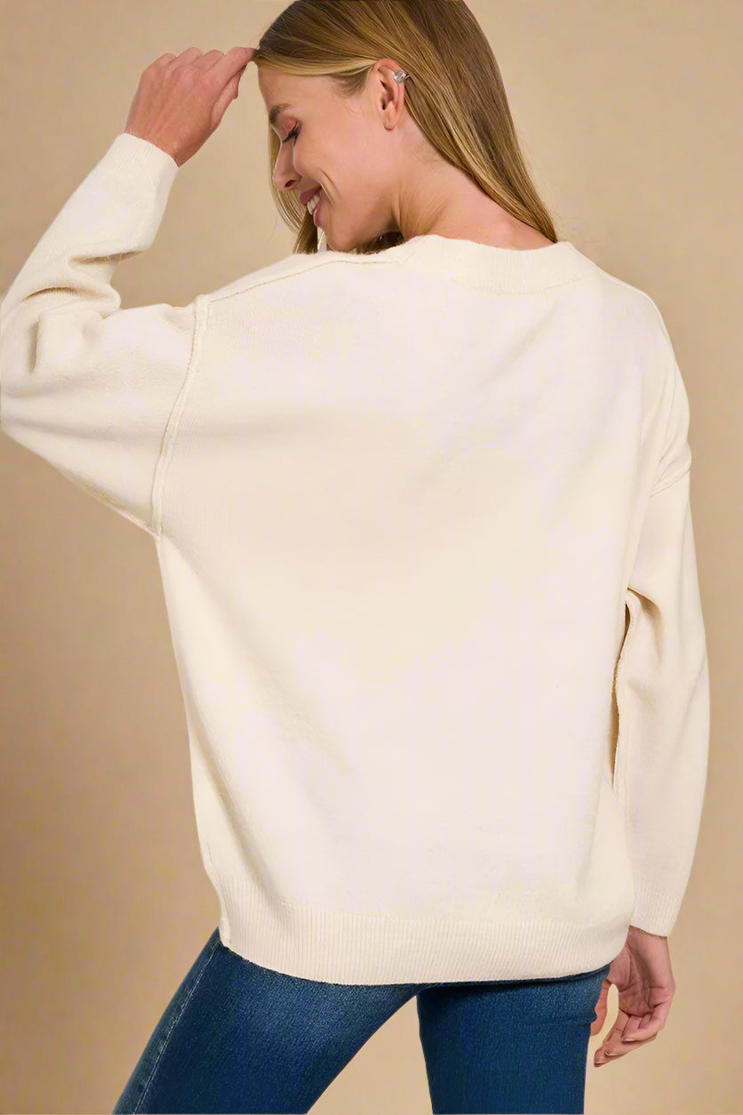 Woman wearing a sand beige sweater with a plain background