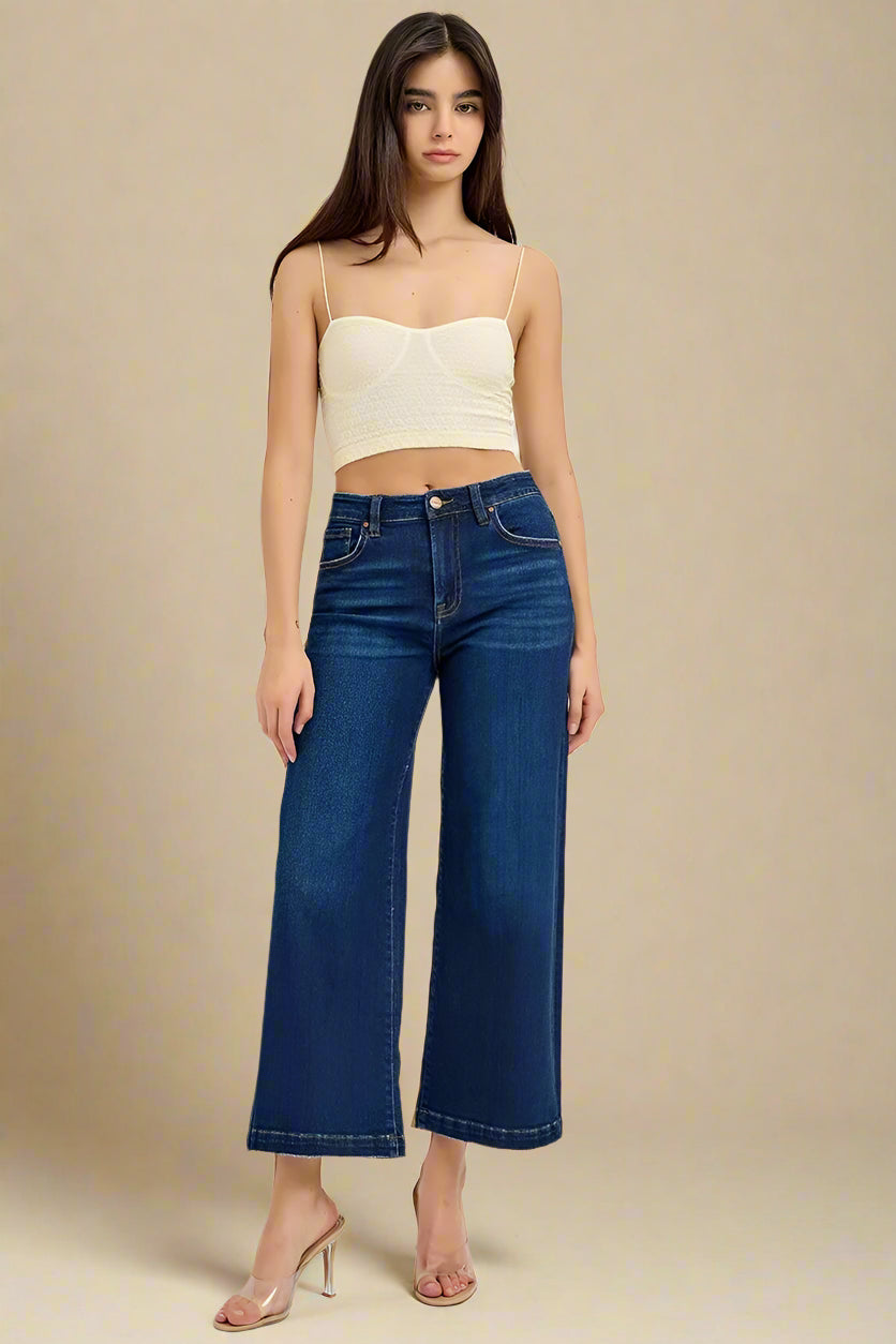 Woman wearing a cream strapless top and blue jeans on a white background