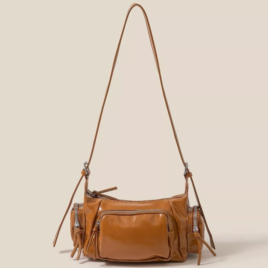Brown leather handbag with multiple pockets and a long strap on a beige background