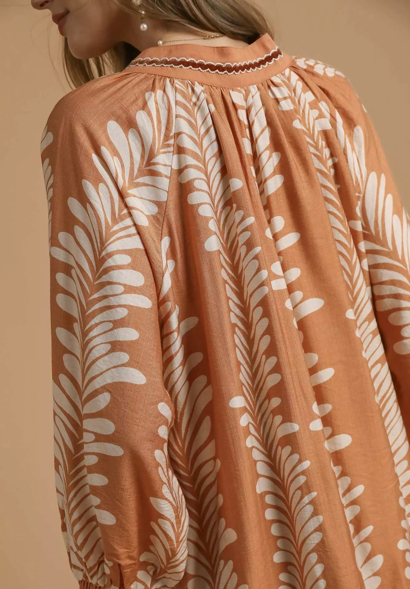 Coral dress with white leaf pattern on a beige background