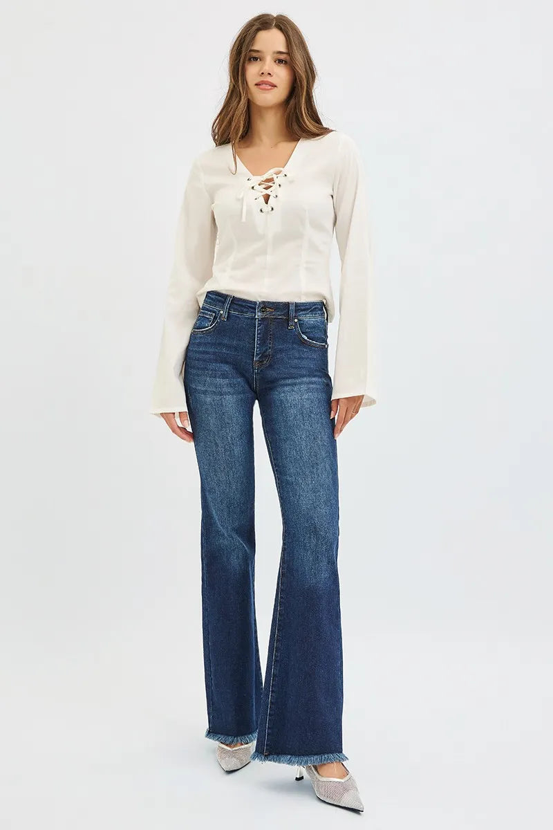 Woman wearing a white lace-up top and blue jeans on a white background