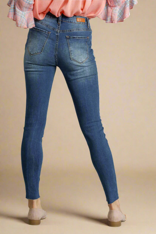 Blue jeans worn by a person on a beige background