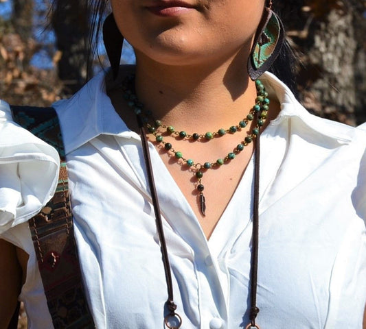 Person wearing a white shirt with a necklace and earrings outdoors