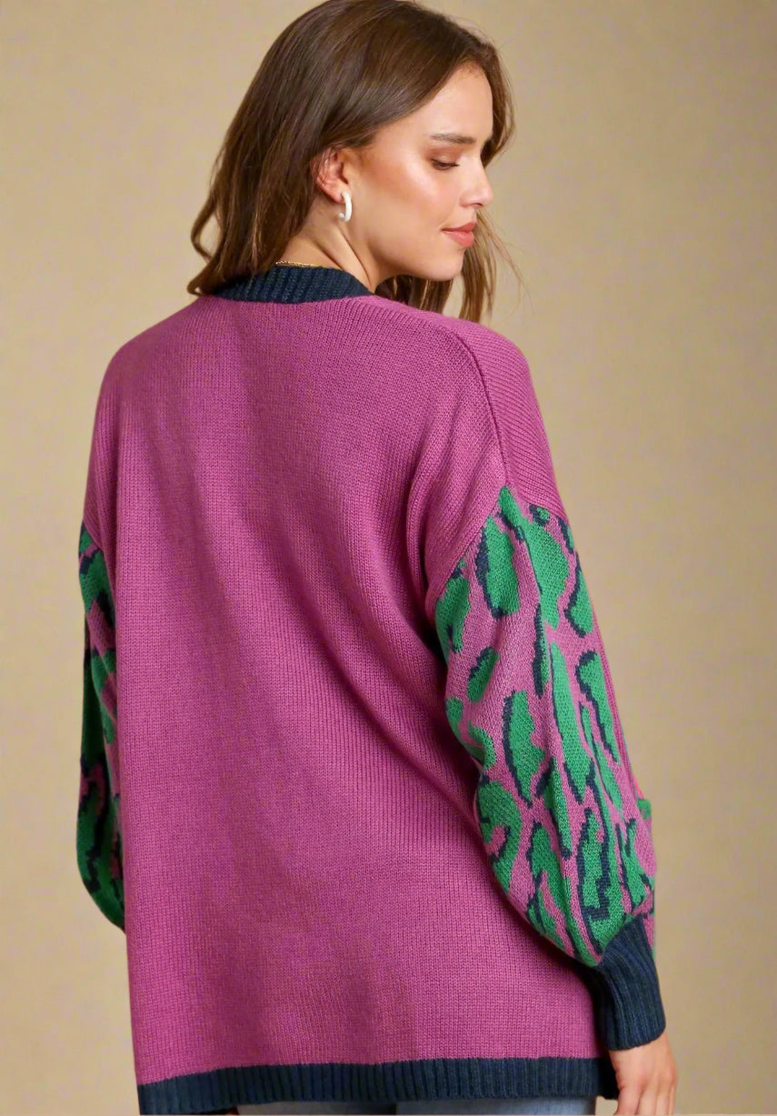 Woman wearing a purple sweater with green patterned sleeves on a beige background