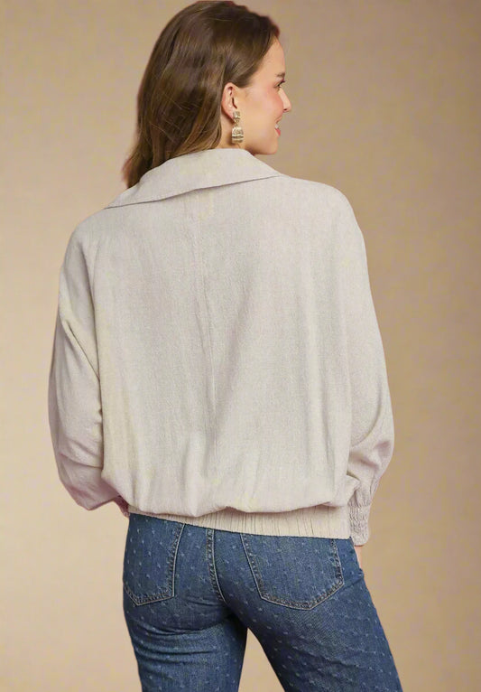 Person wearing a beige blouse and blue jeans against a red background