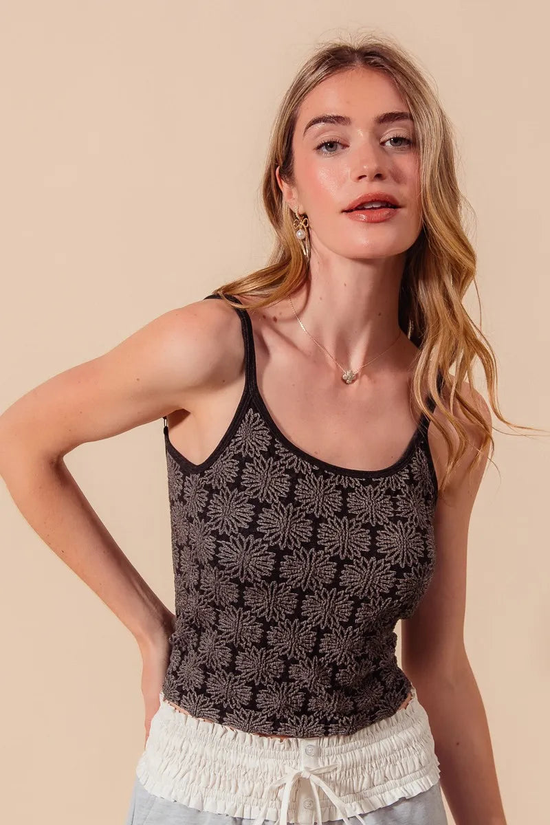 Woman wearing a black floral tank top against a beige background
