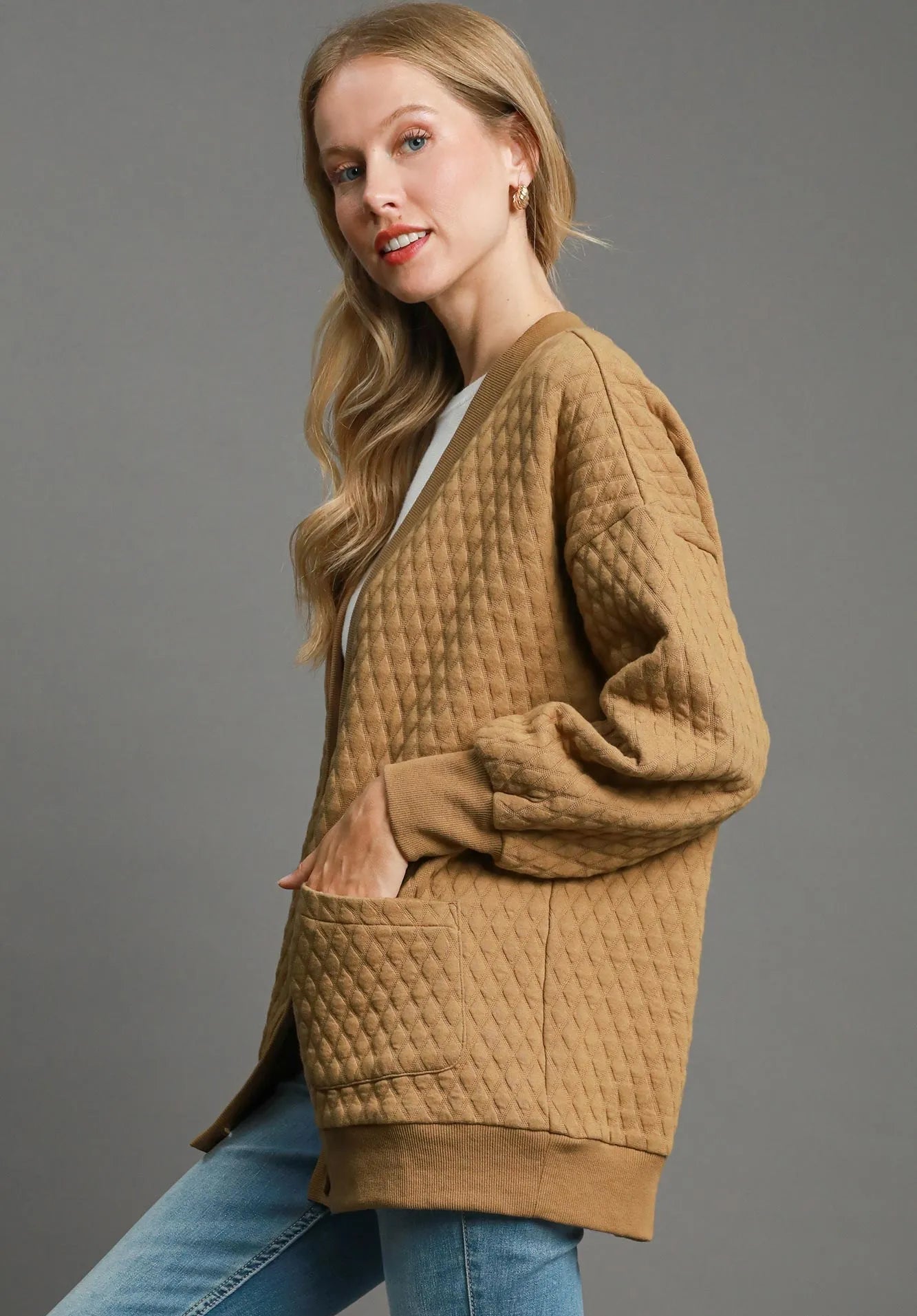 Woman wearing a brown quilted cardigan with a gray background