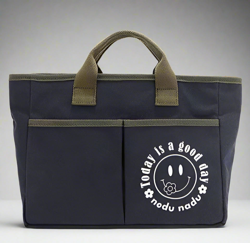 Navy blue bag with green handles featuring a smiley face design on a white background