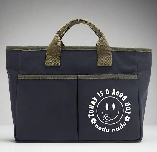 Navy blue bag with green handles featuring a smiley face design on a white background