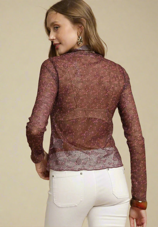 Woman wearing a burgundy sheer top with white pants on a beige background