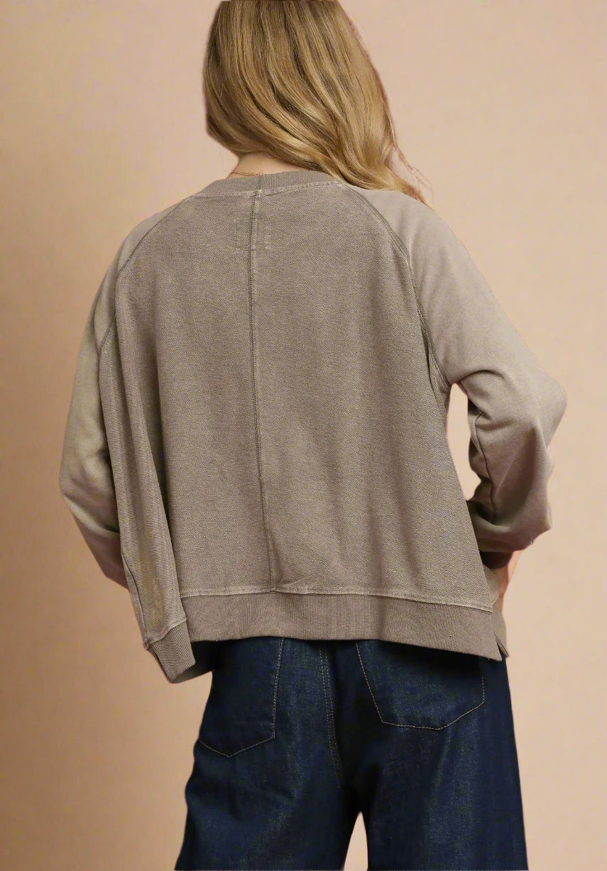 Person wearing a beige sweater and blue jeans against a beige background