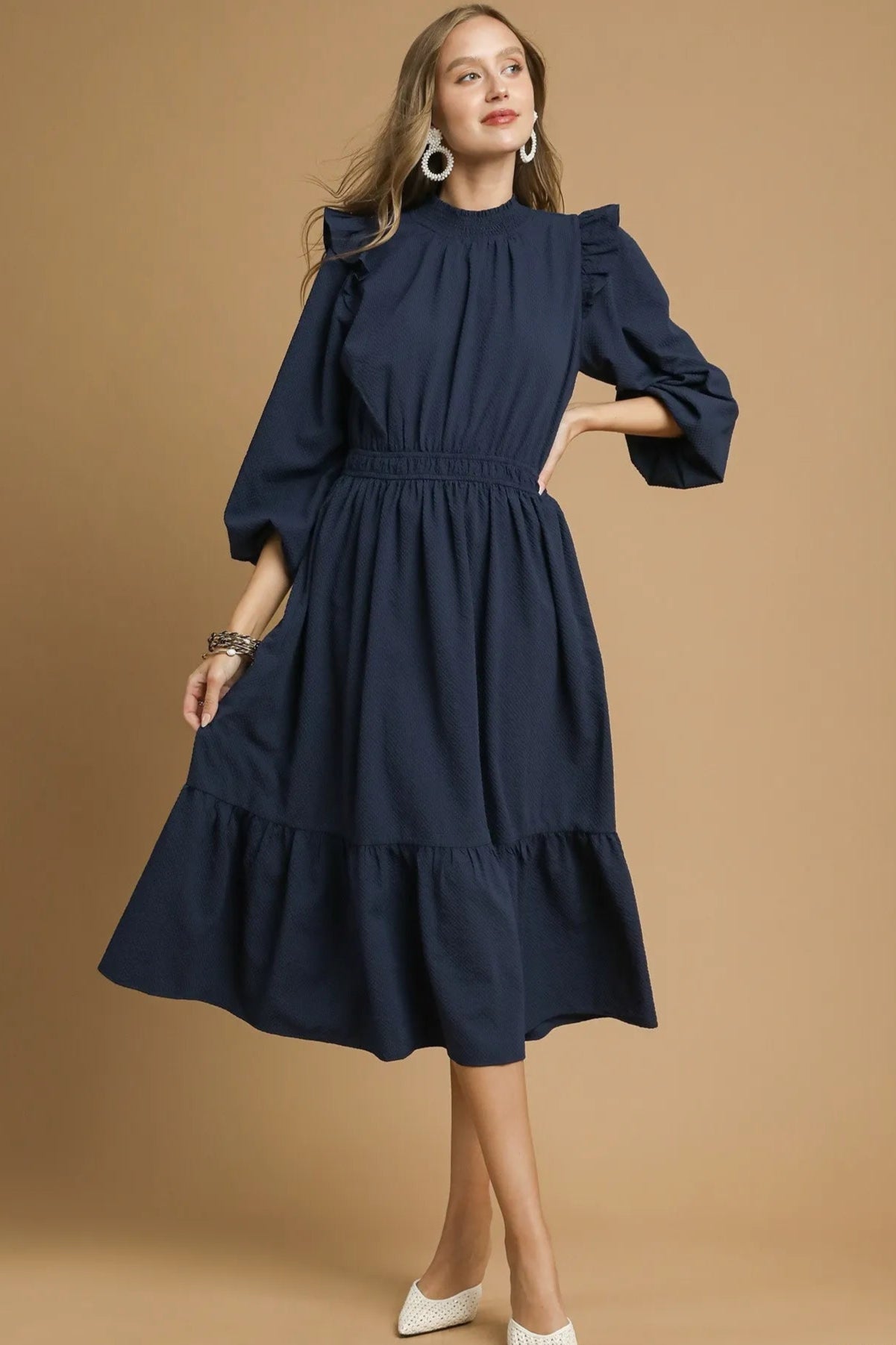 Woman wearing a navy dress on a beige background