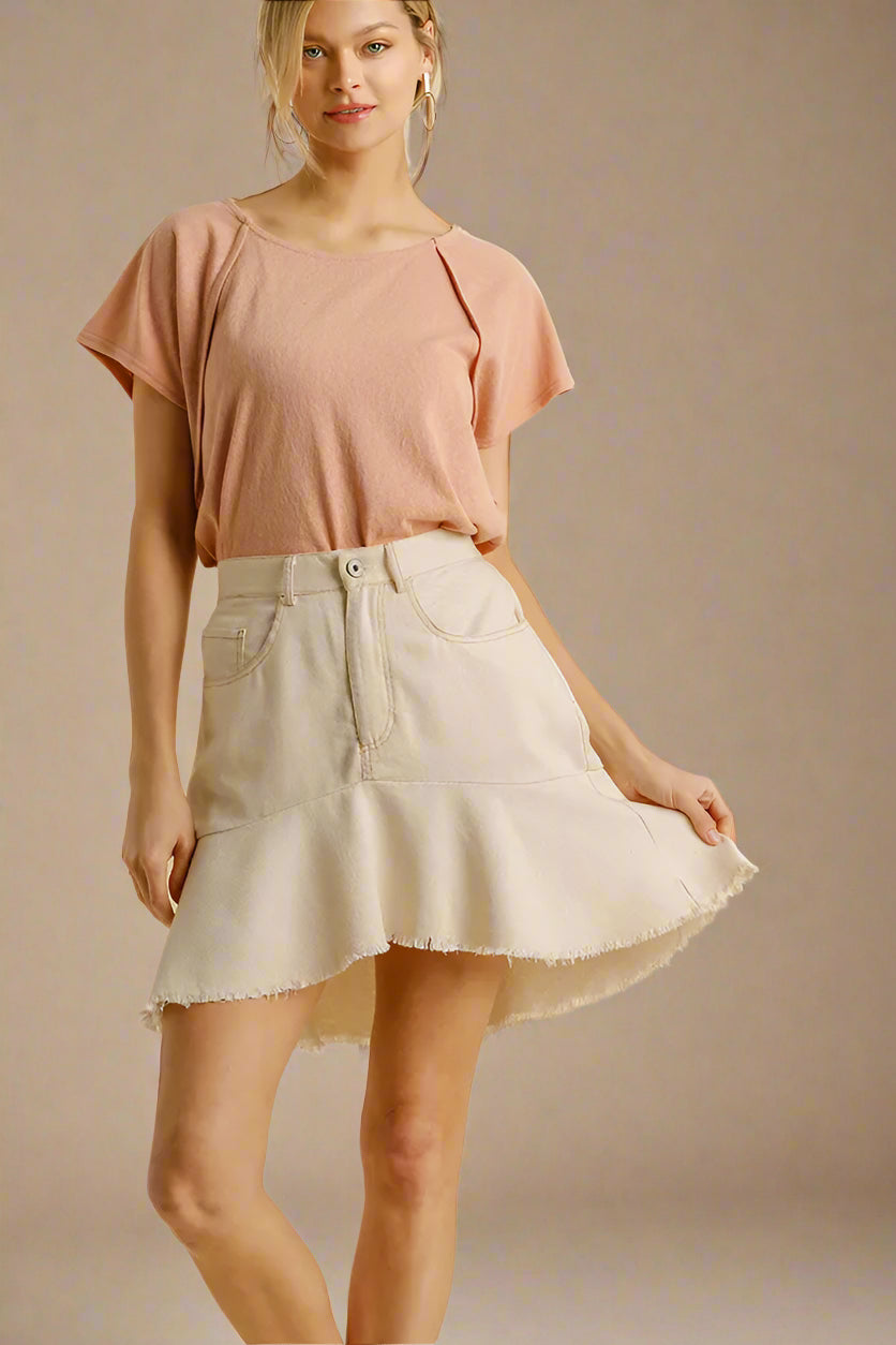 Woman wearing a pink top and beige skirt on a beige background