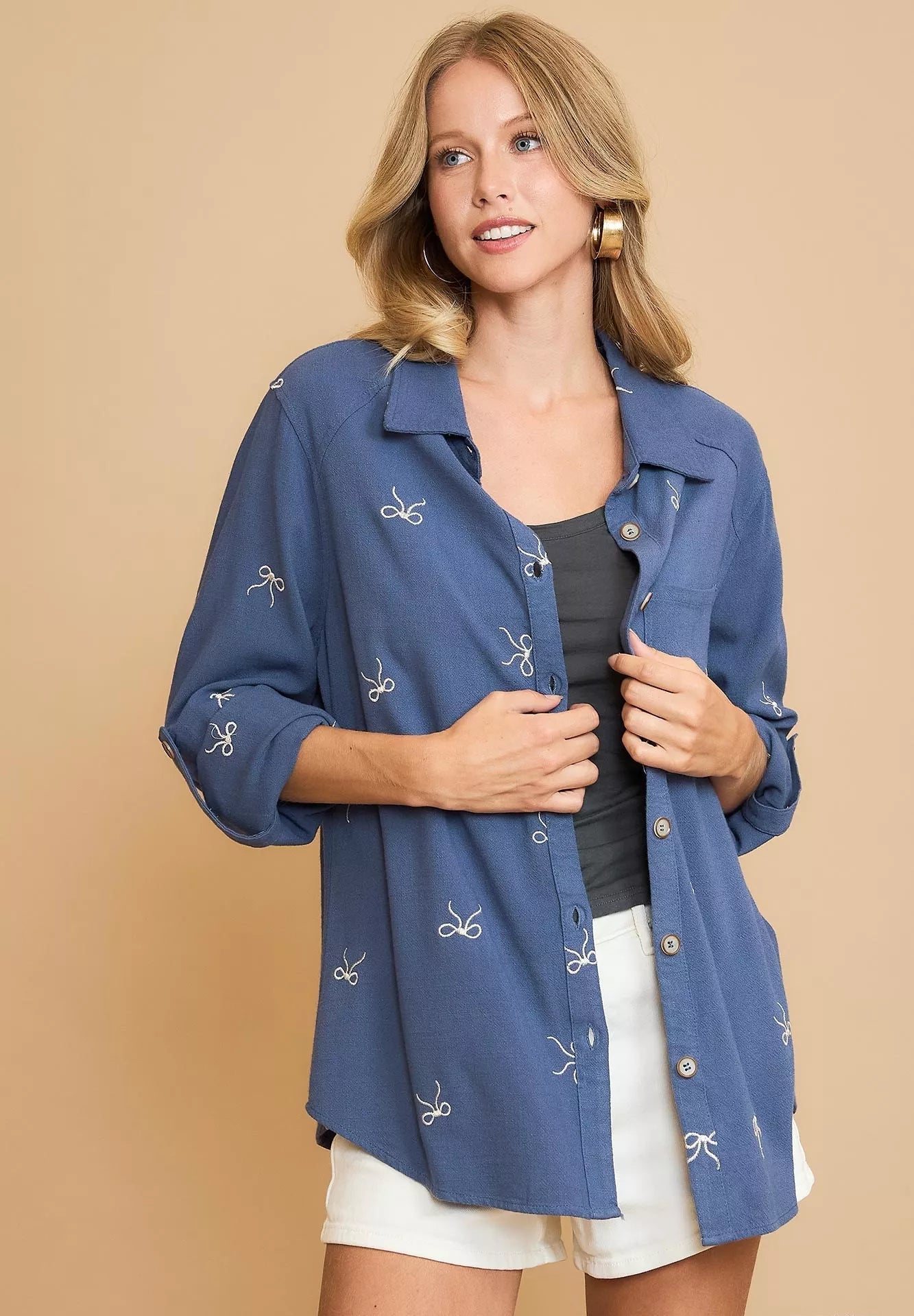 Woman wearing a blue denim shirt with white patterns on a beige background