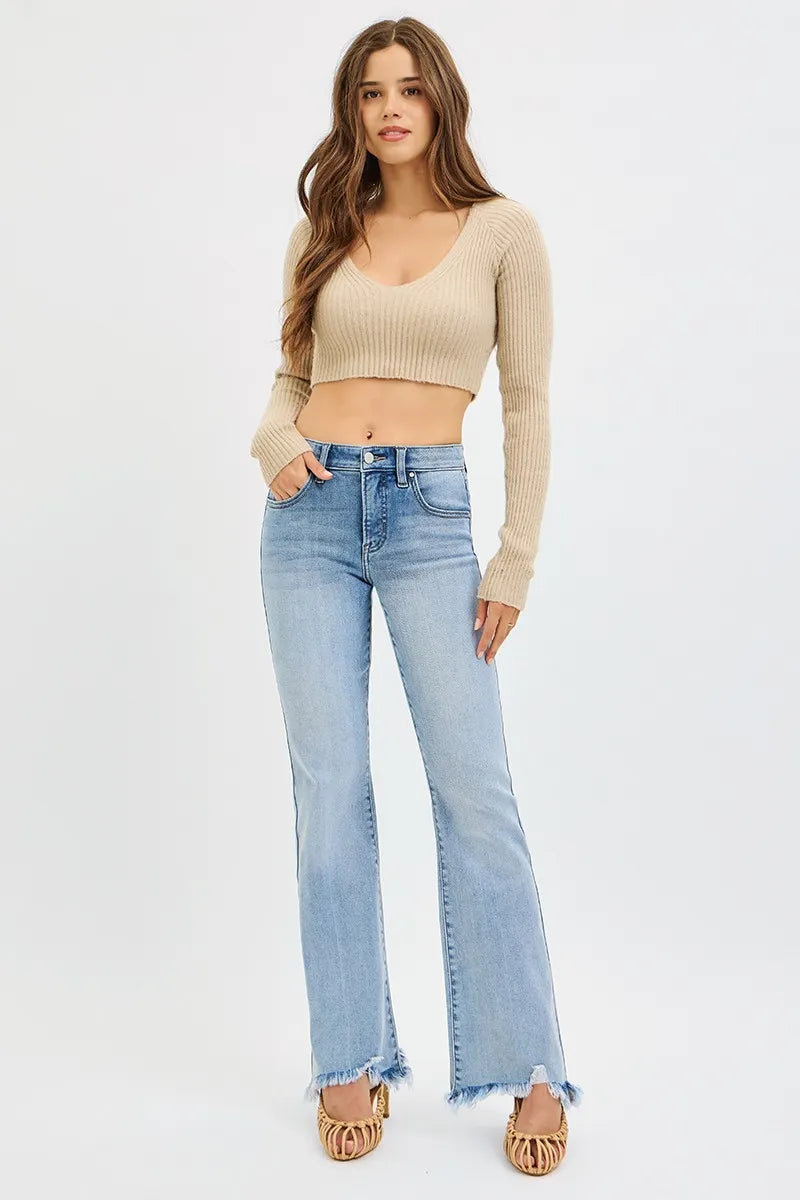 Woman wearing a beige long-sleeve crop top and light blue jeans on a white background