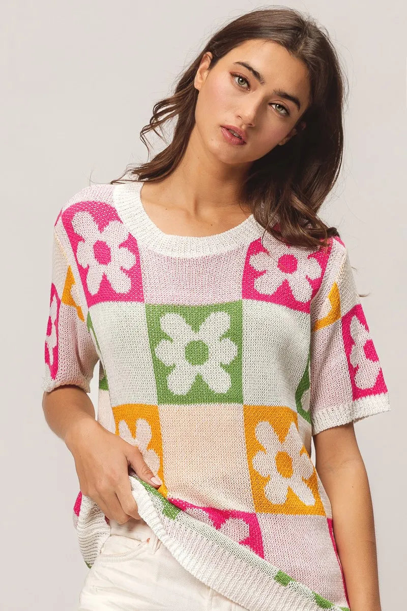 Woman wearing a colorful floral-patterned sweater on a plain background