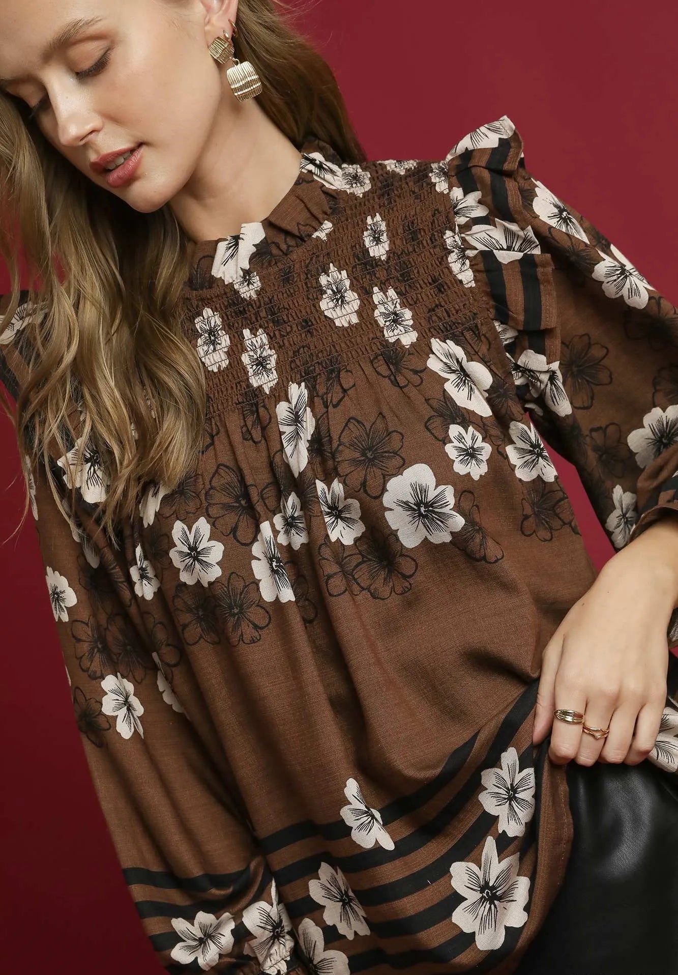 Woman wearing a brown floral blouse against a red background
