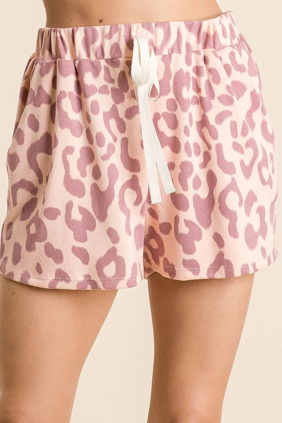 Pink leopard print shorts with a white drawstring on a beige background