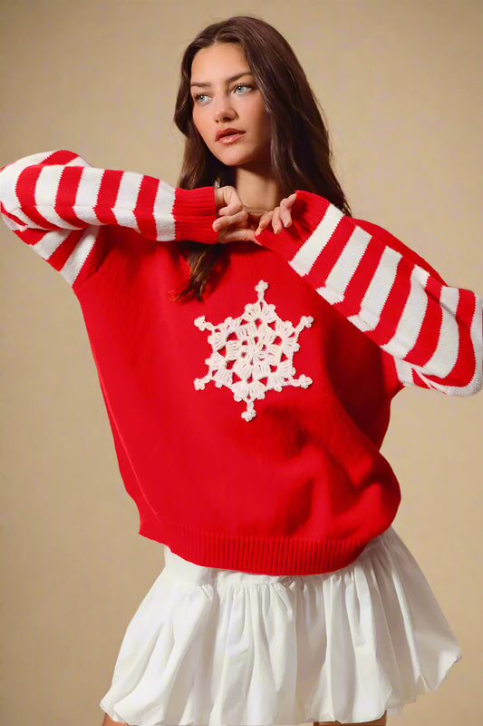 Woman wearing a red sweater with white snowflake design and white skirt against a beige background