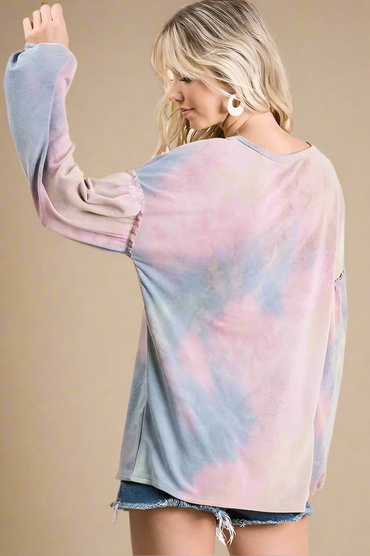 Person wearing a tie-dye long-sleeve shirt with a plain background