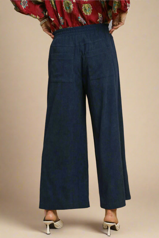 Navy blue wide-leg pants worn with a patterned top on a beige background