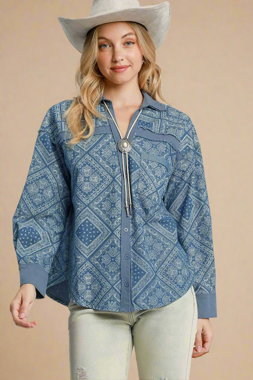 Woman wearing a blue patterned shirt with a silver tassel and a white cowboy hat on a beige background