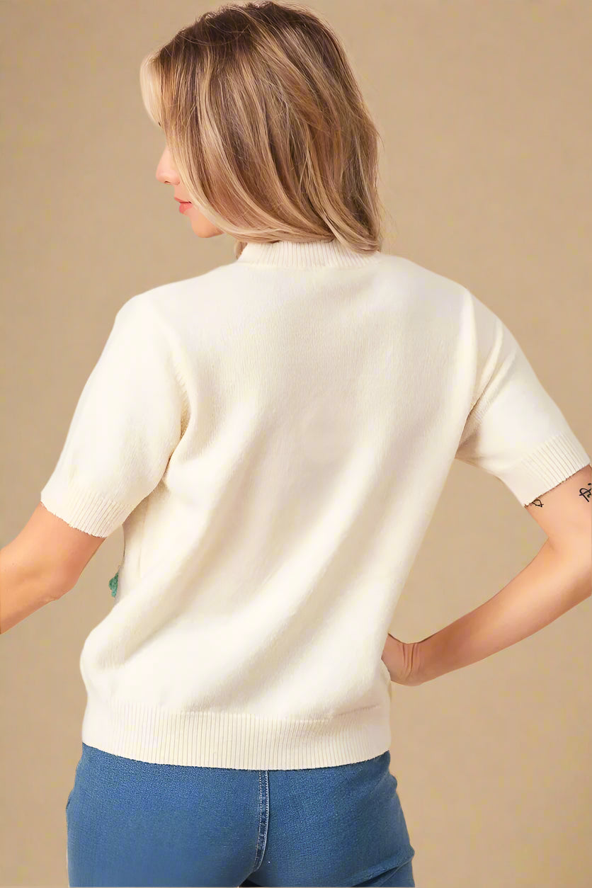 Woman wearing a cream sweater and blue jeans against a beige background