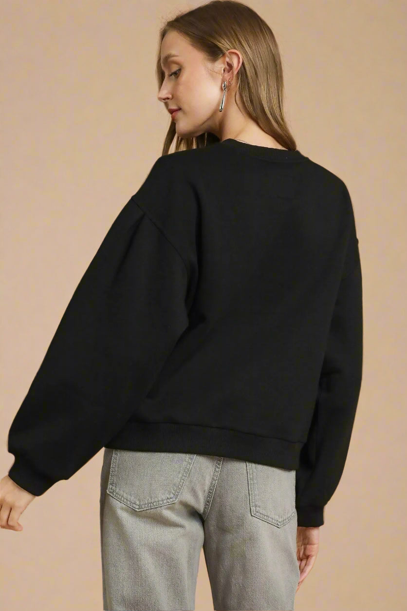 Person wearing a black sweatshirt and gray pants on a beige background