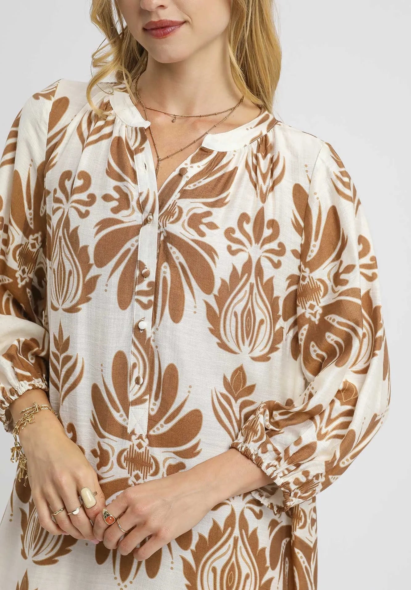 Woman wearing a patterned dress with long sleeves on a white background