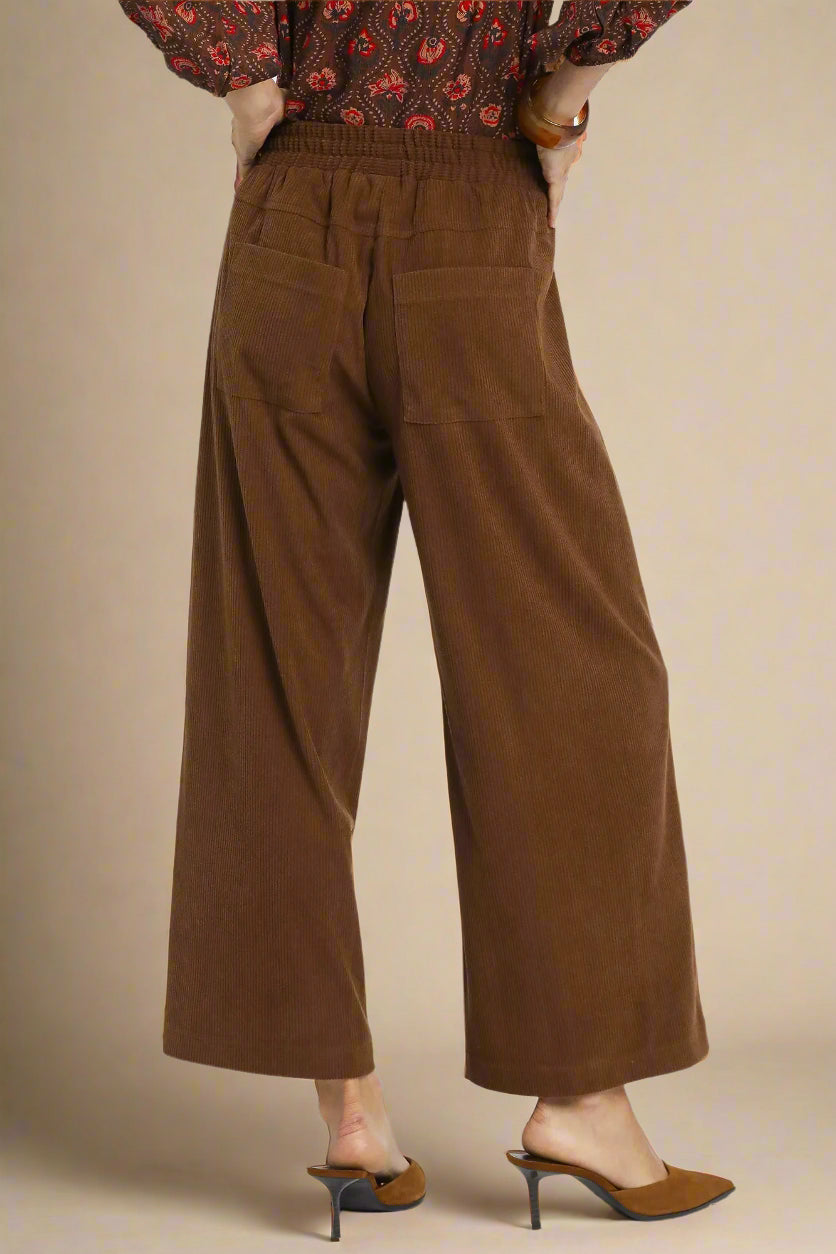 Brown wide-leg pants worn by a person on a beige background