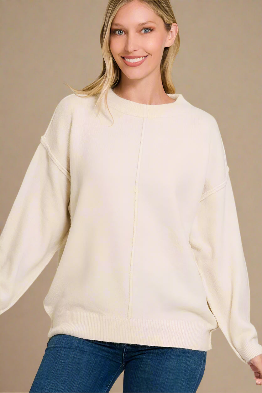 Woman wearing a sand beige sweater with a plain background