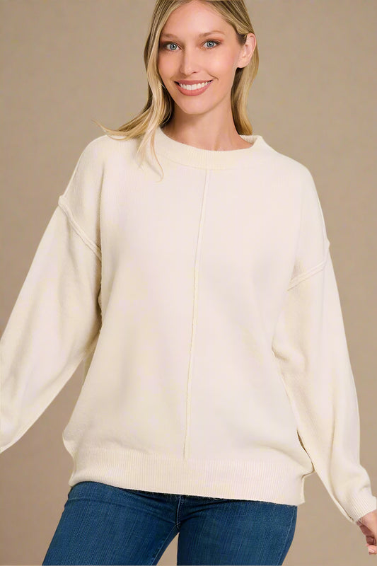 Woman wearing a sand beige sweater with a plain background