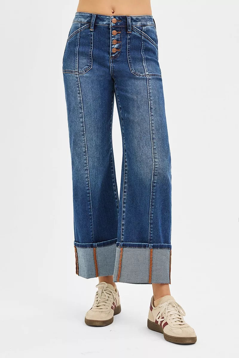 Wide-leg blue jeans with button details on a white background