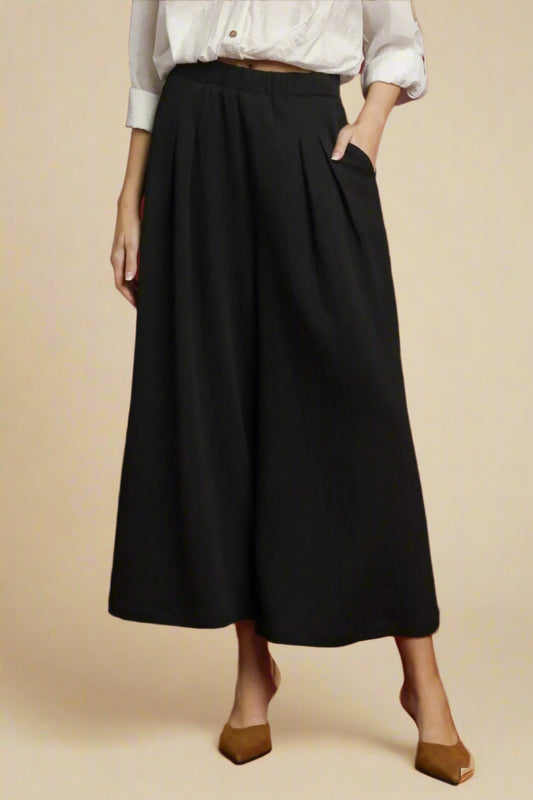 Person wearing black pants with a white shirt on a beige background