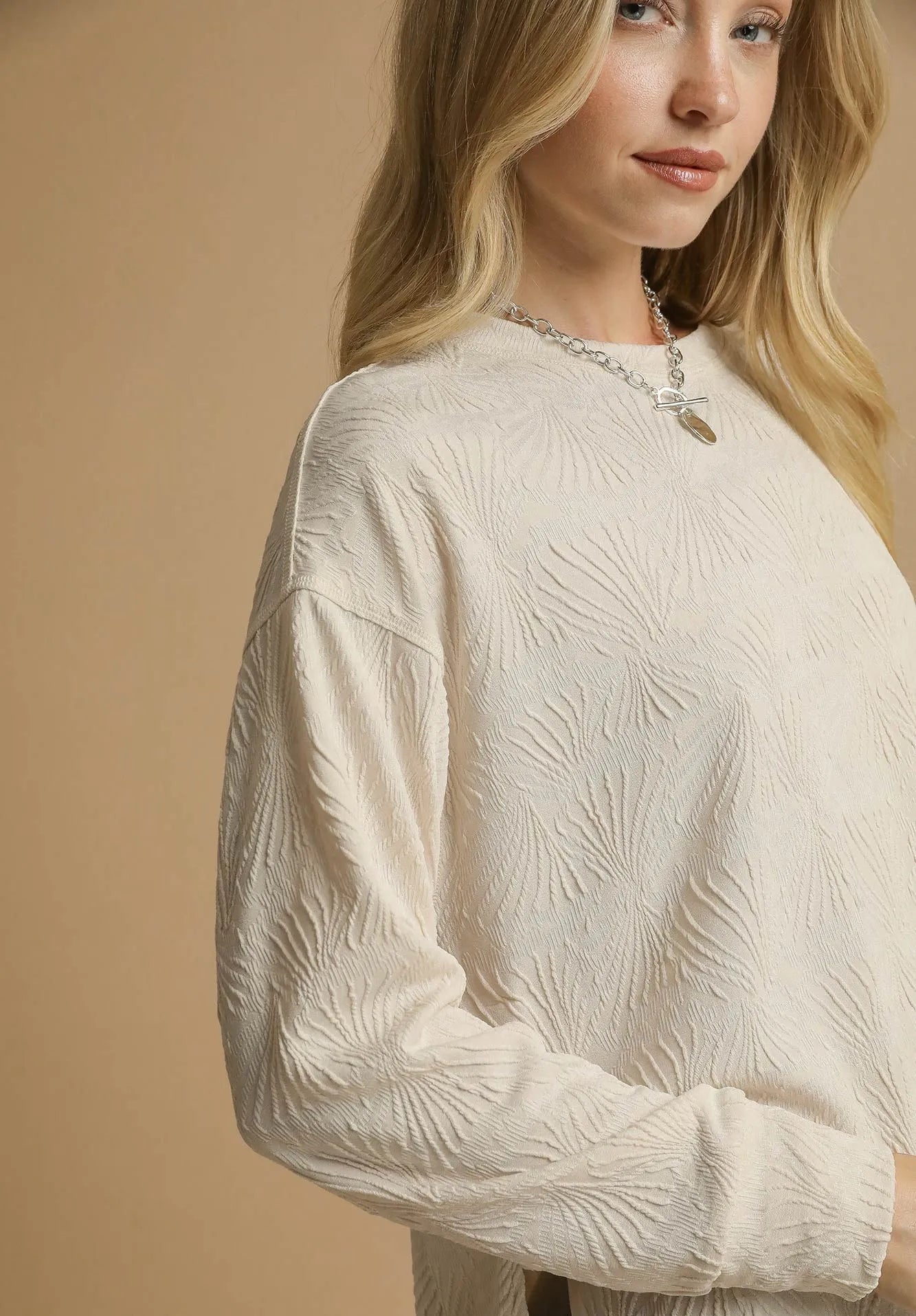Woman wearing a textured beige sweater against a beige background