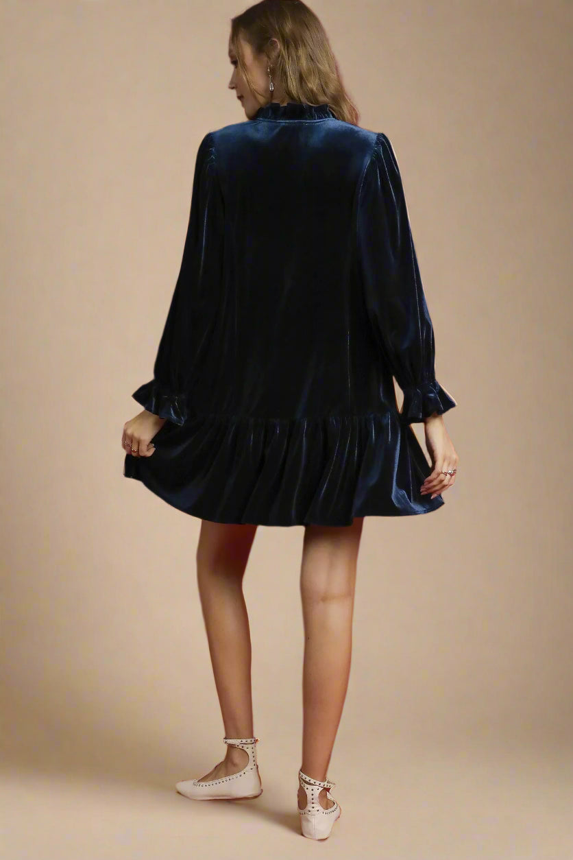 Woman wearing a navy velvet dress against a beige background