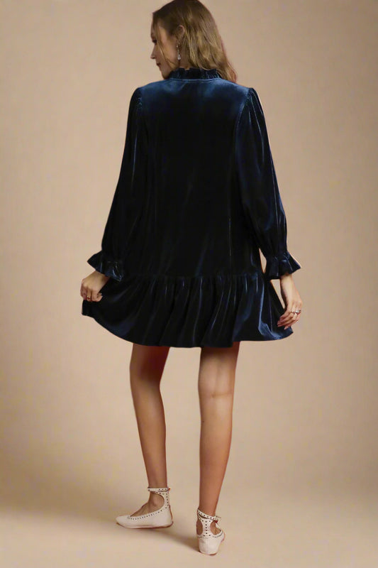 Woman wearing a navy velvet dress against a beige background