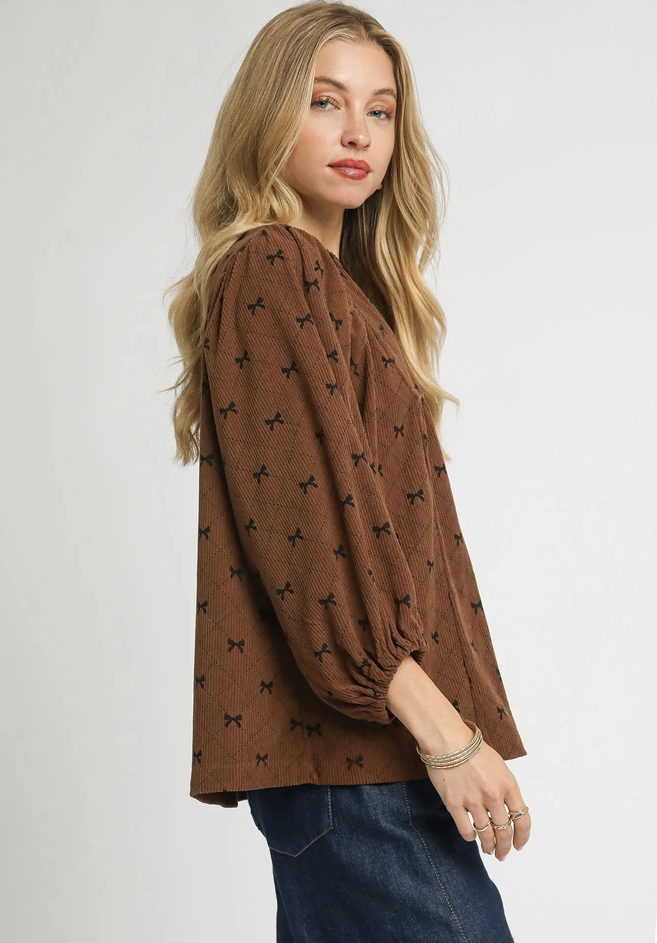 Woman wearing a brown blouse with black patterns on a white background