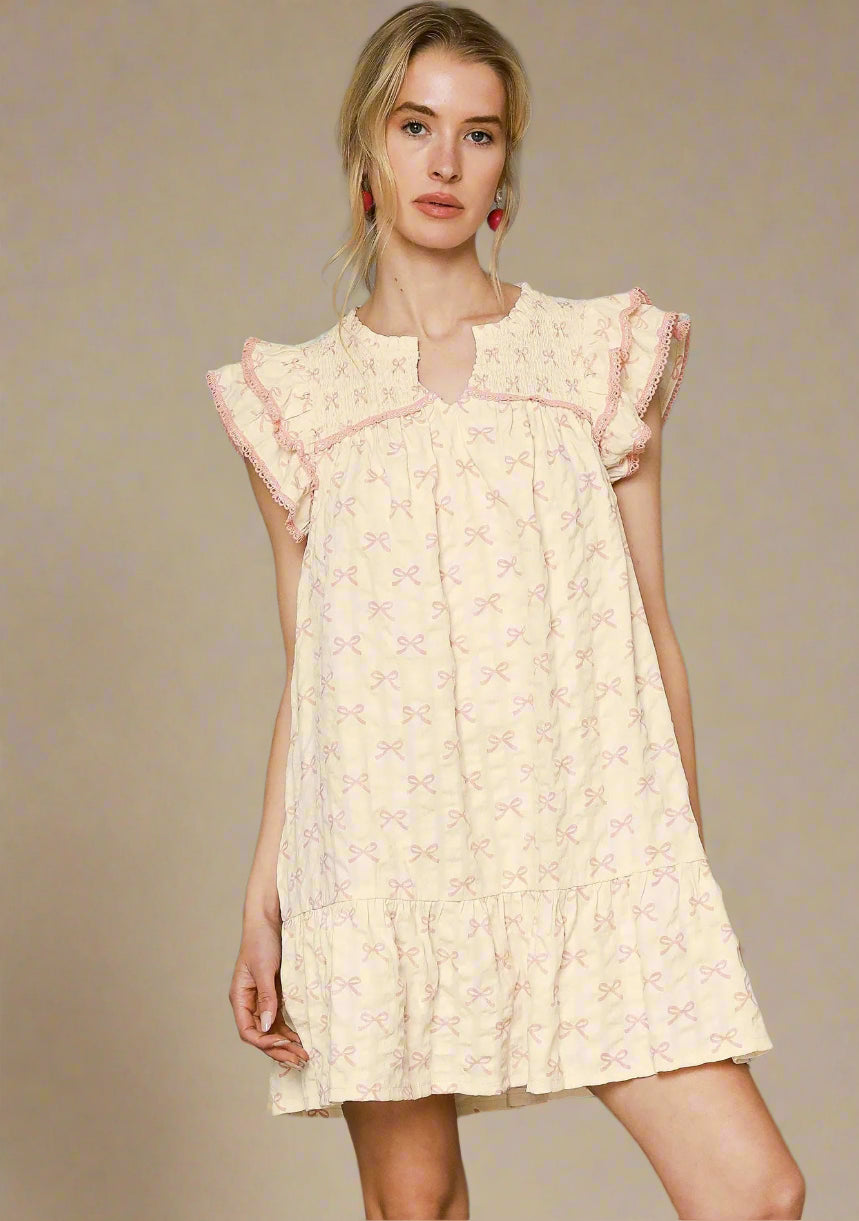 Woman wearing a light-colored dress with pink accents against a beige background