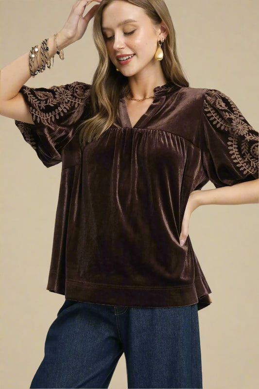 Woman wearing a brown velvet top with lace sleeves on a white background