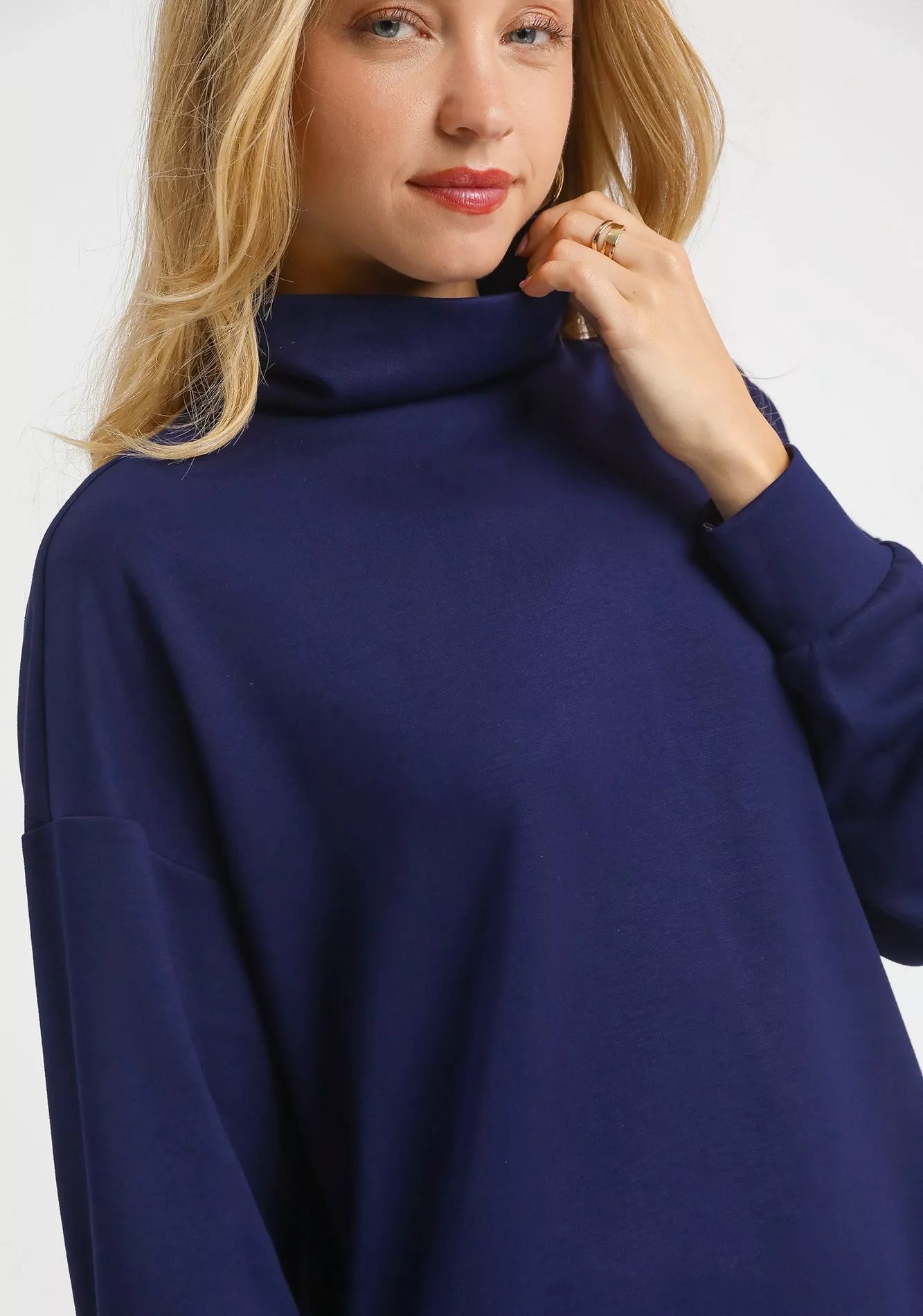Woman wearing a navy blue turtleneck sweater on a white background