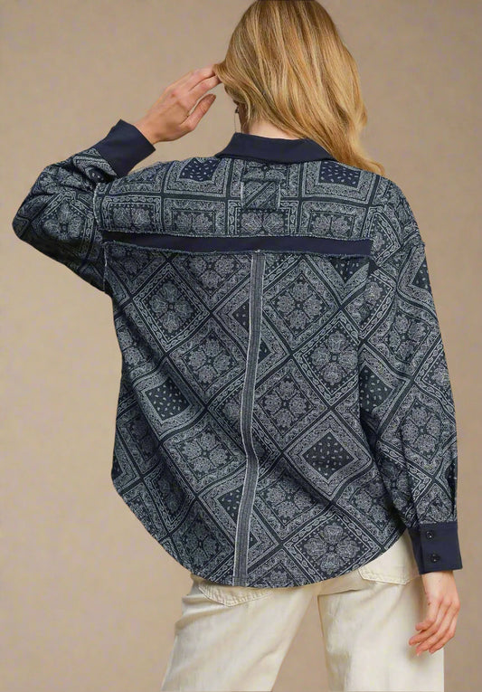 Person wearing a dark denim patterned shirt against a beige background