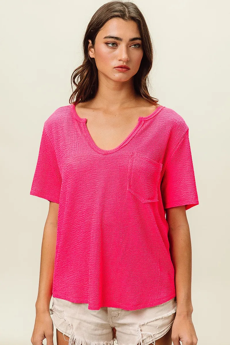 Woman wearing a bright pink textured top against a plain background
