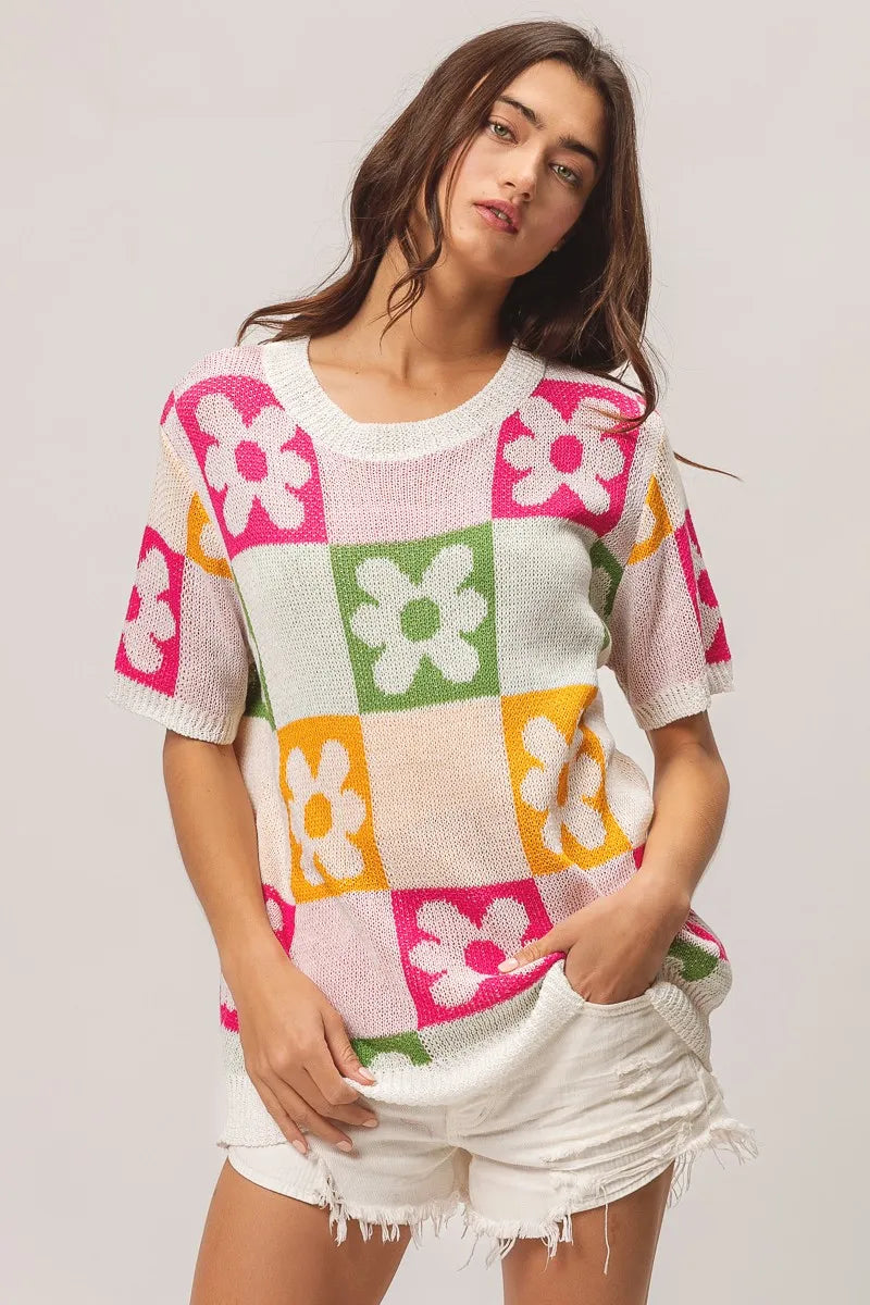 Woman wearing a colorful patchwork sweater with a plain background