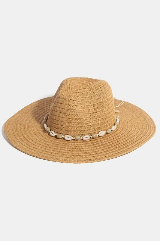 Beige straw hat with a shell embellishment on a light gray background