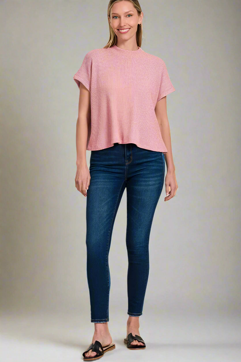 Woman wearing a light rose top and blue jeans on a white background