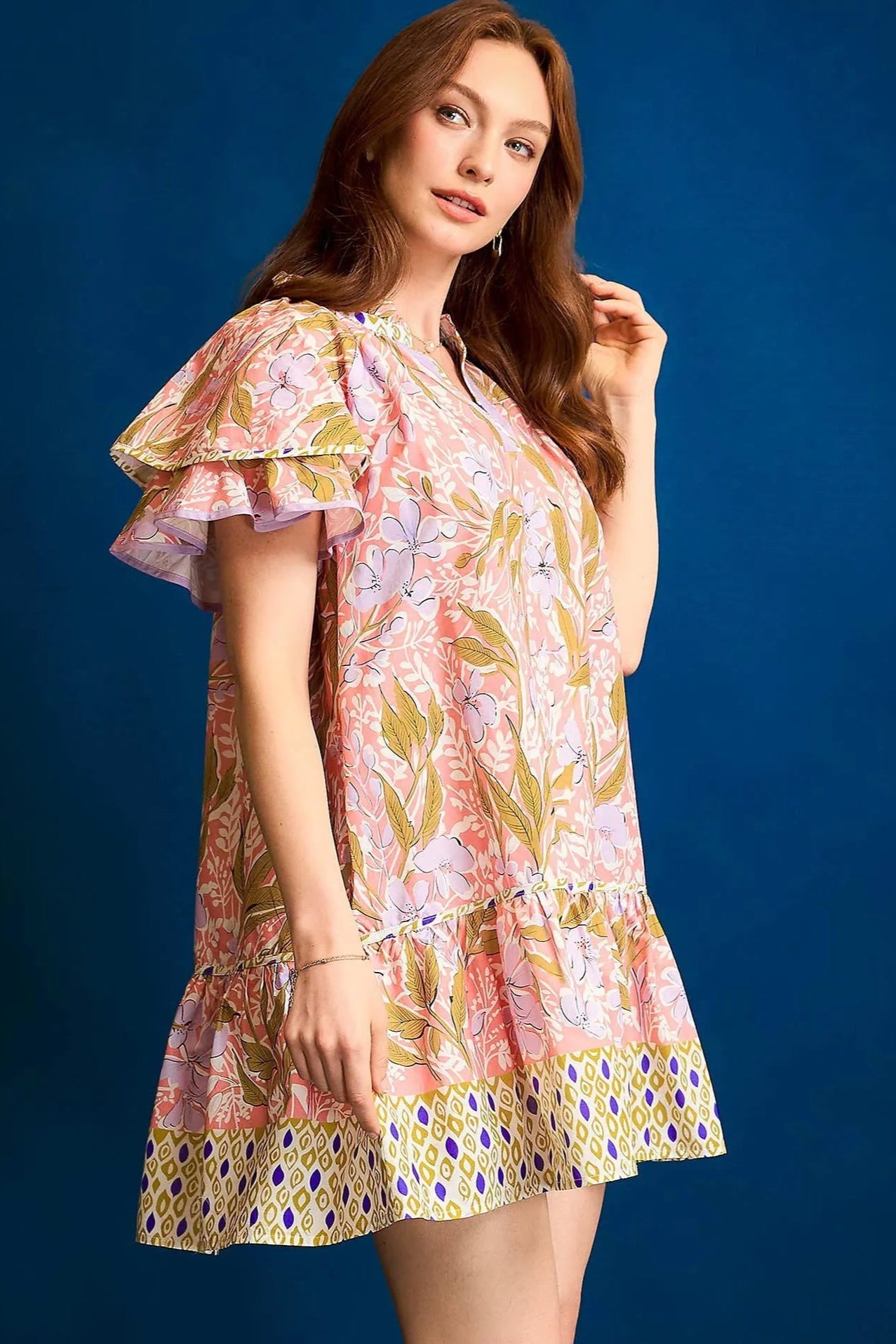 Woman wearing a colorful floral dress against a blue background